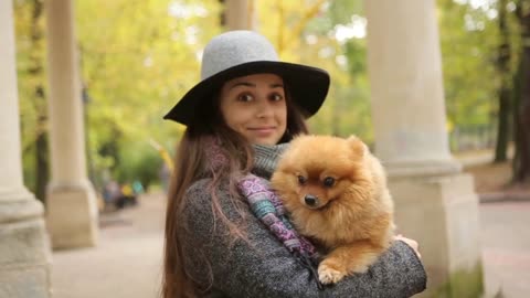 Teenage girl with hat holds the dog on his hands look at camera smile happy nature