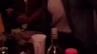 Guy at party flips a yellow cup on top of alcohol bottle