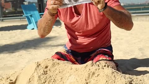 A Man Digging Money From The Sand