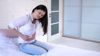 Woman having a stomach ache on the bed