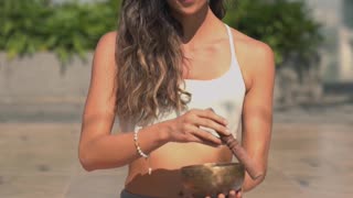 A Woman Meditating while Using a Healing Bowl