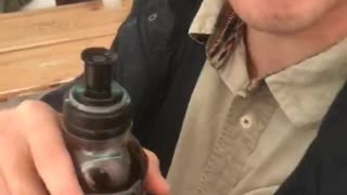 Guy holding bottle with dark liquids makes weird sounds and faces