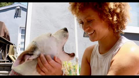 BIPOC woman rubs dog's head while smiling