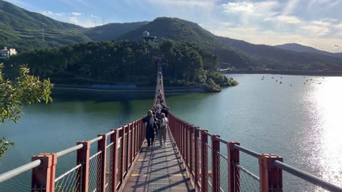 people crossing the rocking bridge over the lake