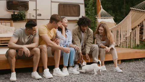 Group Of Multicultural Friends Playing With Jack Russell Terrier Dog At Camping