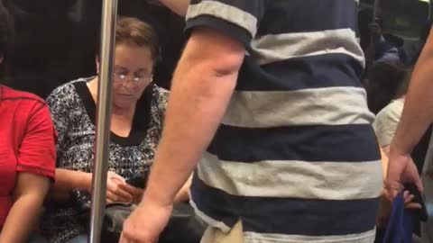 Guy grey and blue striped shirt polo falling asleep standing up holding onto pole subway train