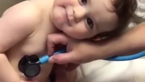 Baby lays on nurse's hand during examination _shorts