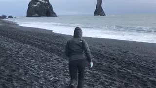 Woman runs on sand at the beach, jumps and falls