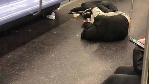 Guy lays on the floor in subway train