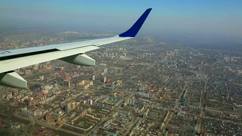 Wing view of an airplane flying above the city