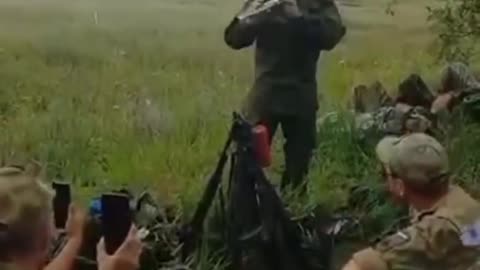 A Russian medic plays the flute for a group of soldiers during their rest in the rear.