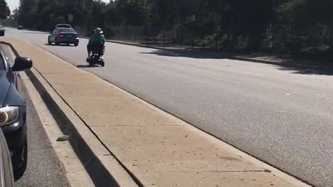 Blissfully Unaware Senior Rides Scooter on Highway