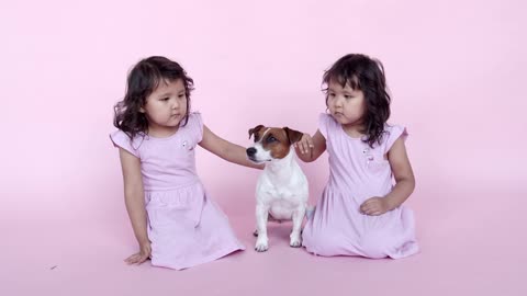 Twin girls playing with dog