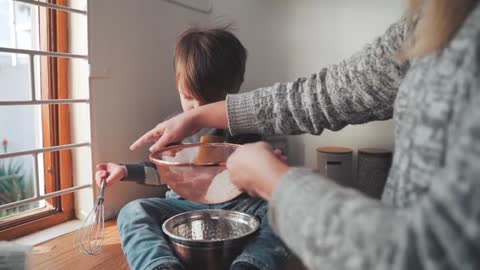 A small child helps his mother with cooking