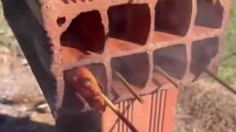 Cooking sausages on a fire in a brick