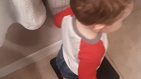 A 23-month-old boy steps on the scale, not happy with the holiday weight