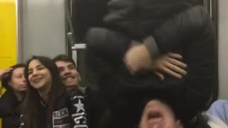 Guy black jacket hangs upside down subway train