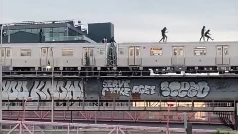 Subway surfers atop of a subway car in graffiti emblazoned NYC