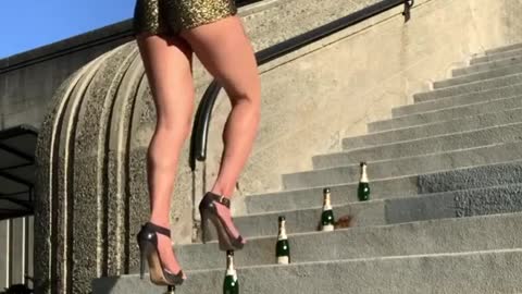 Woman wear high heals and walk on bottles place over staircase