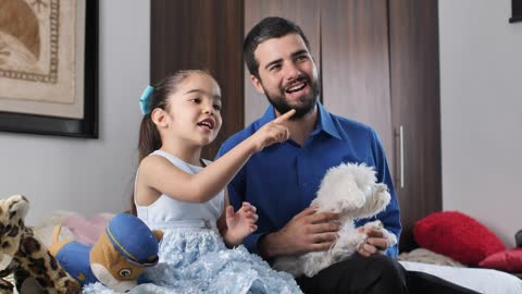 Father and daughter together watching television with their little dog