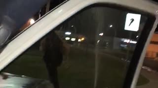 Girl runs through sprinklers toward truck and slips