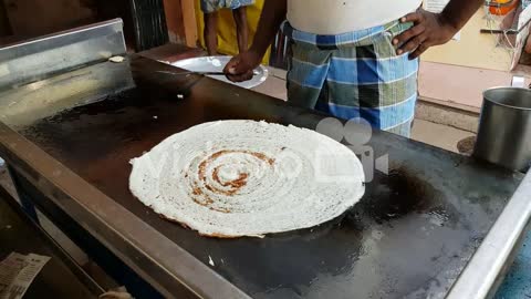 A man making dosa on a huge stone plate-