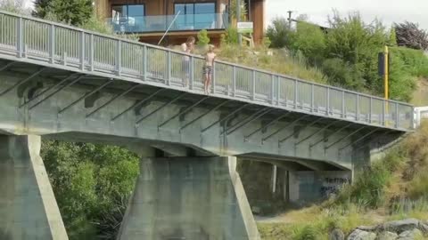 Teenager jumps into water from a bridge