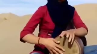 Girl playing Tombak in desert