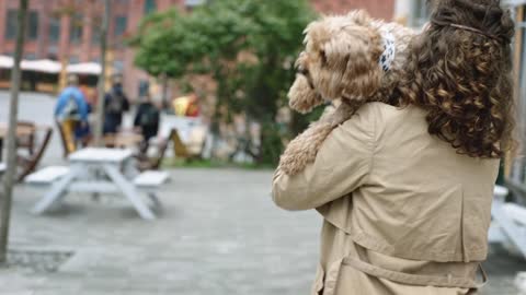 Woman Carrying Her Dog While Walking In The Street