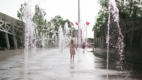 Girl walking in rain-dance fountain