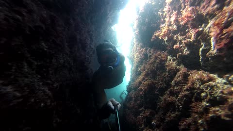 Dangerously tight squeeze diving underneath caves