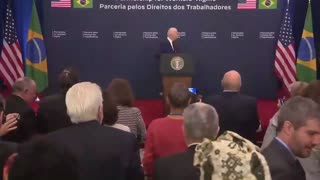 Biden walks on stage w/o the Brazilian president, almost knocks down flag, then does a little jog