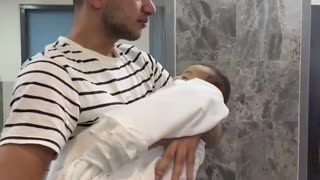 Palestinian man holds 9 month old son Hamza killed in Israeli air raids