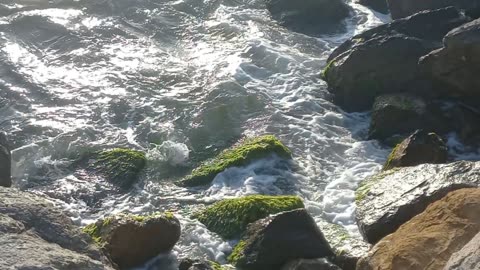 The sea waves on the rocks and the sunlight are a calm and deep view
