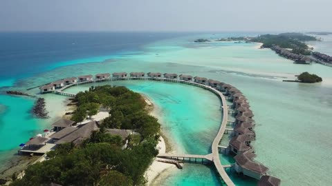 Aerial view of tropical island resort hotel with white sand palm trees and turquoise Indian Ocean