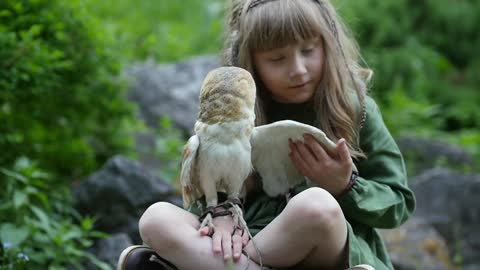 Little girl with an owl in a fairy forest. Friends