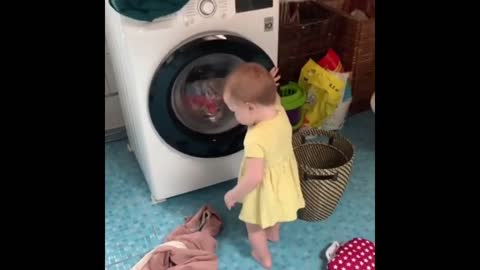 Precious baby helps her mom with the laundry