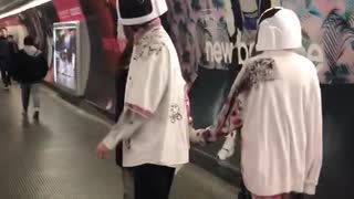 Couple wearing daft punk like helmets walks down subway station