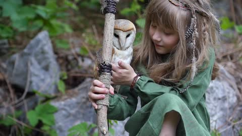 Little girl with an owl in a fairy forest. Friends