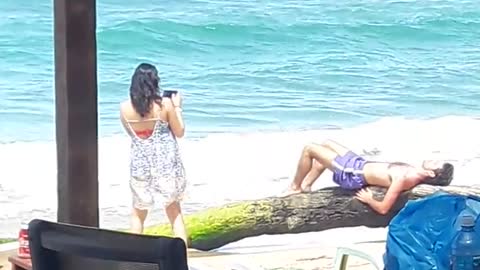 Girl taking picture for guy in blue shorts laying on rocks
