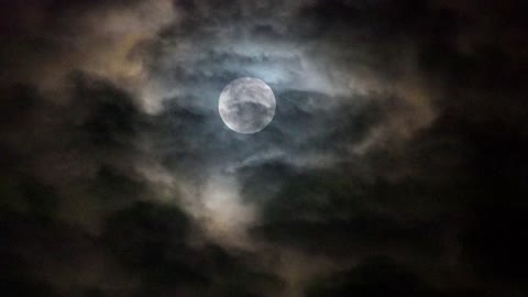 a dark clouds over shadowing the full moon