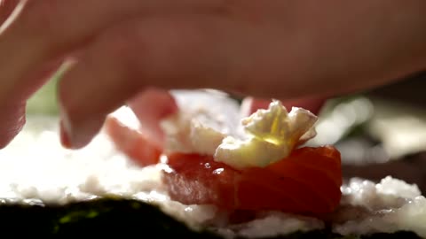 Adding fish and cheese to a Sushi Roll