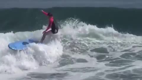 Guy in pink black wet suit surfboard slapping wave