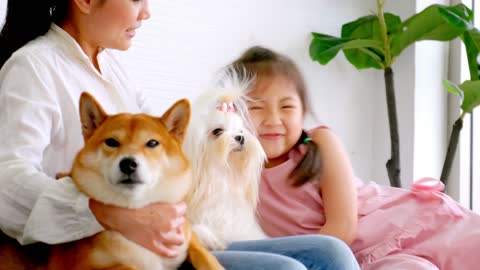 Mother and little daughter with their dog spending time together at home.