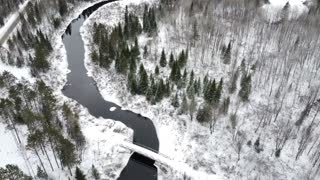 Bridge across the forest river covered in snow
