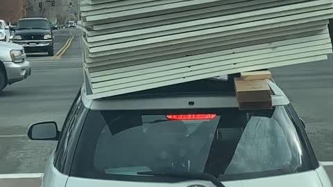 Building Supplies Barely Balanced on Car Roof