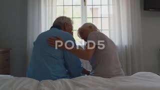 Worried Retired Senior Couple sitting on Bed at home