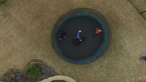 Drone above kids playing on a trampoline.