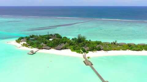 A luxury tourist island with a pier and bungalows