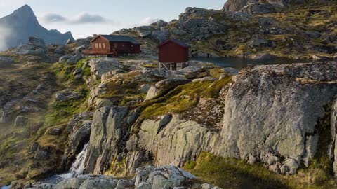 scenic summer shot of clouds passing by a mountain hut on the lofoten islands norway